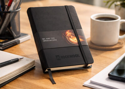 Branded ROCKWOOL notebook on a wooden desk next to a coffee cup