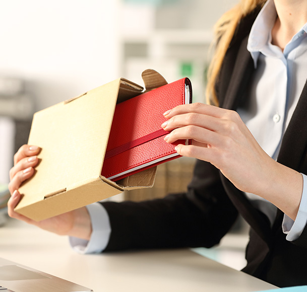 Hands unboxing a red branded notebook from a kraft box