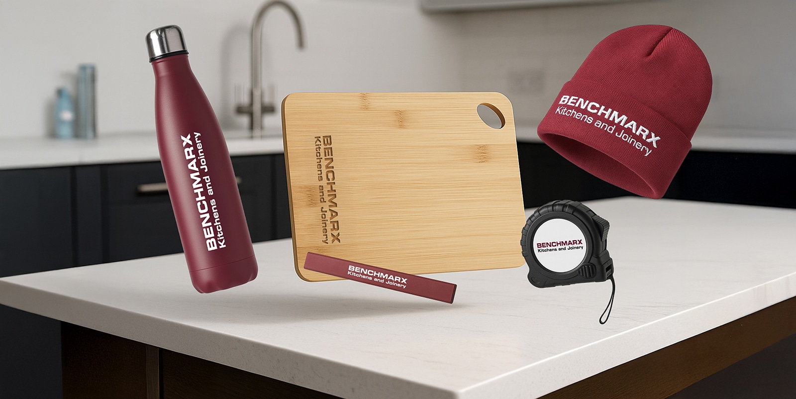 Benchmarx branded merchandise collection: thermal bottle, bamboo chopping board, pencil, beanie and tape measure on a kitchen counter